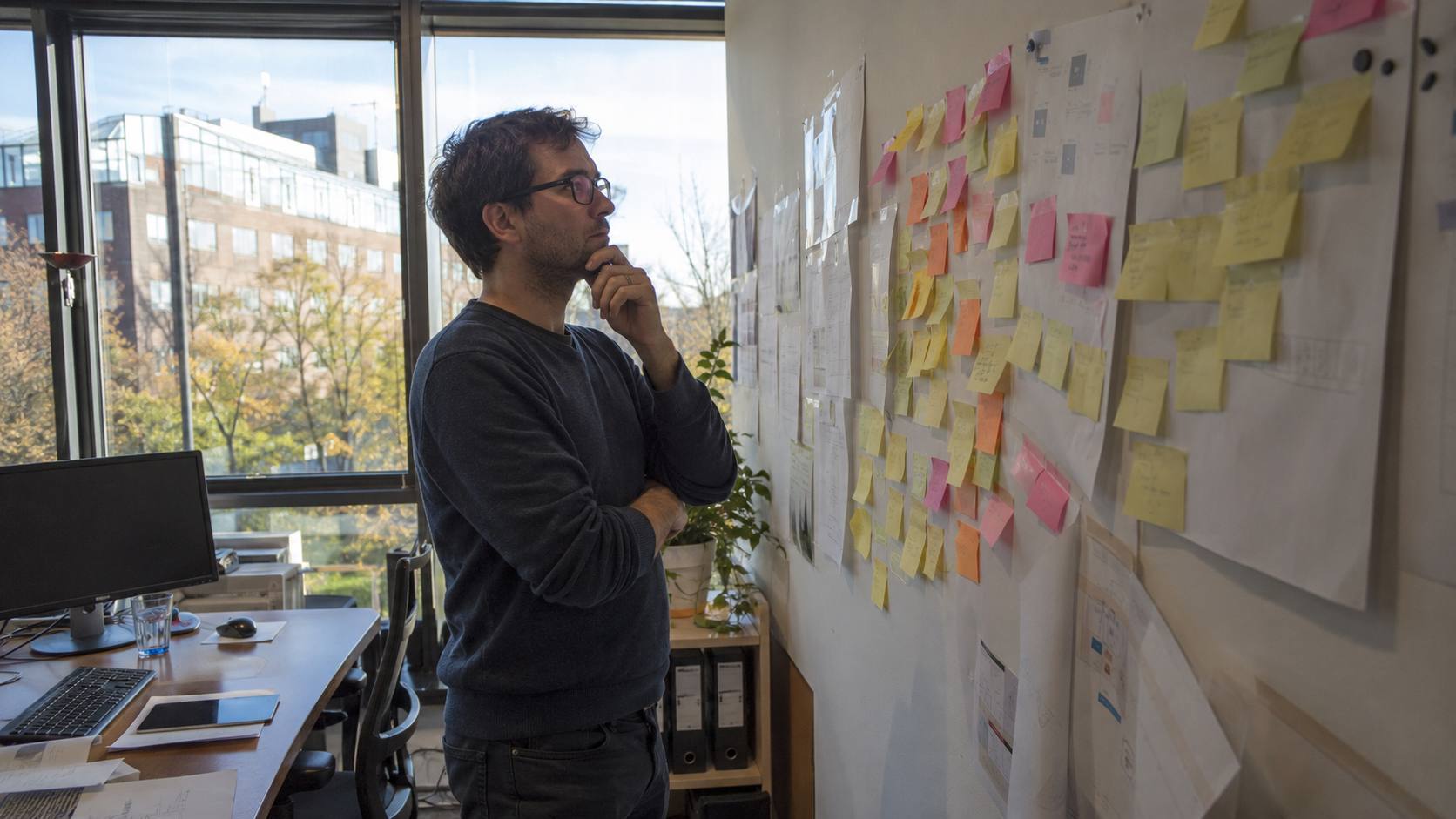 Consultant planifiant plusieurs mois de contenu à l'avance devant un mur de post-it organisés par période