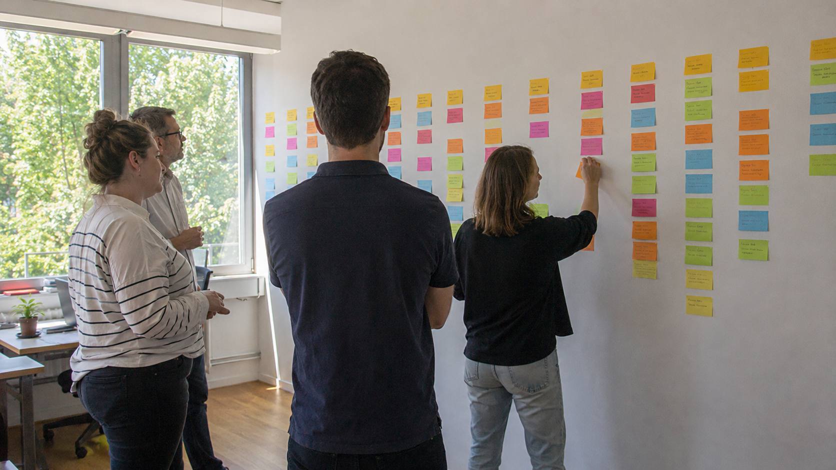 Équipe planifiant des contenus sur un mur de post-it colorés disposés en colonnes